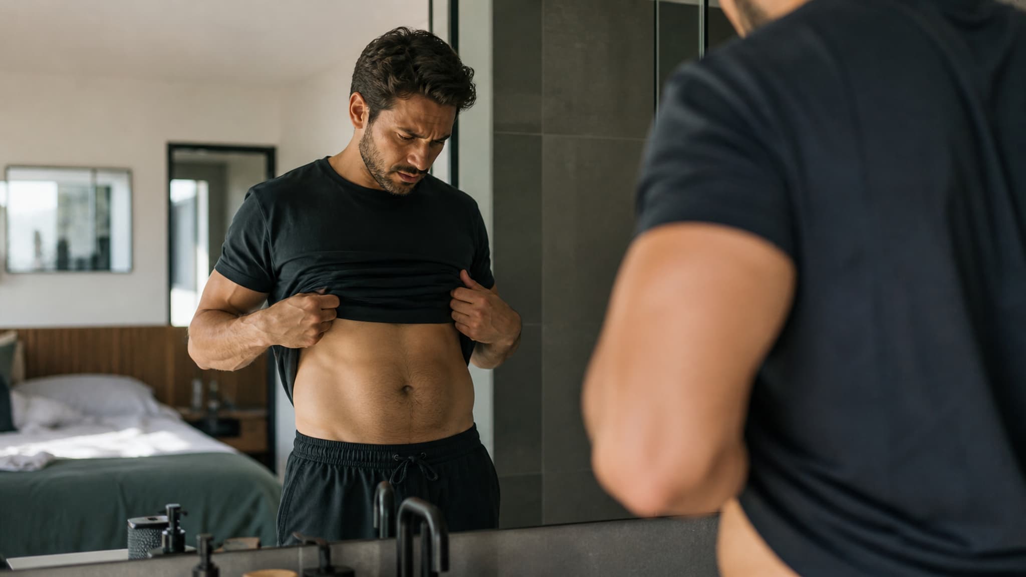 A person examining their midsection, frustrated by chronic bloating masking fat loss progress