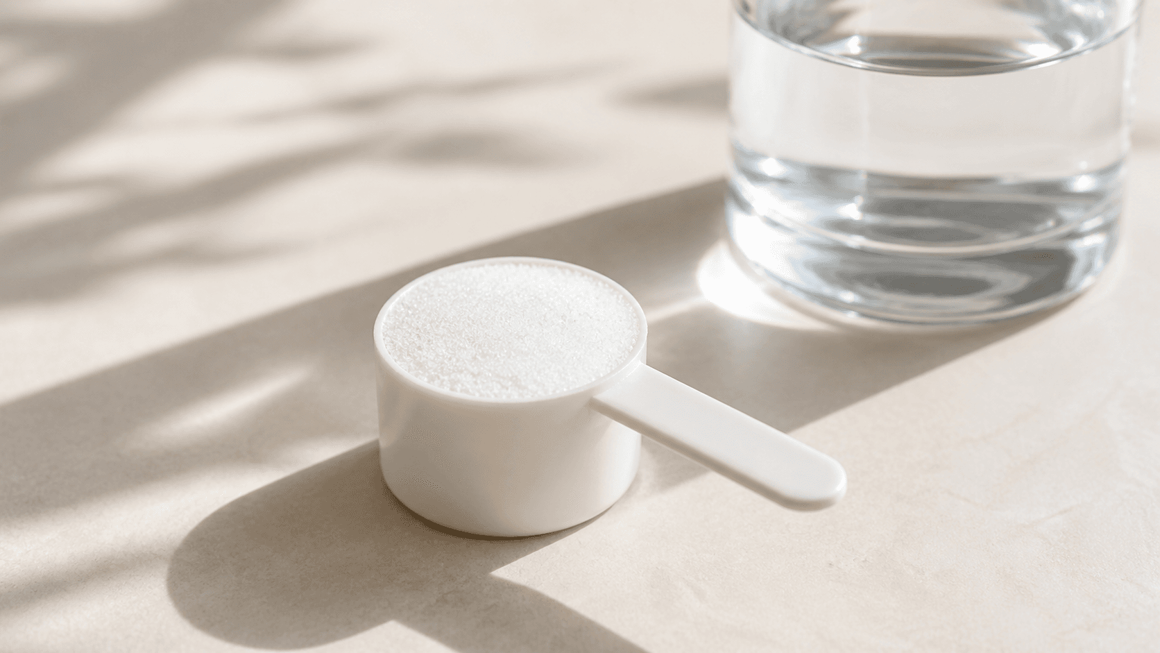 A close-up of pure creatine monohydrate powder next to a glass of water, conveying the simplicity and purity of the supplement
