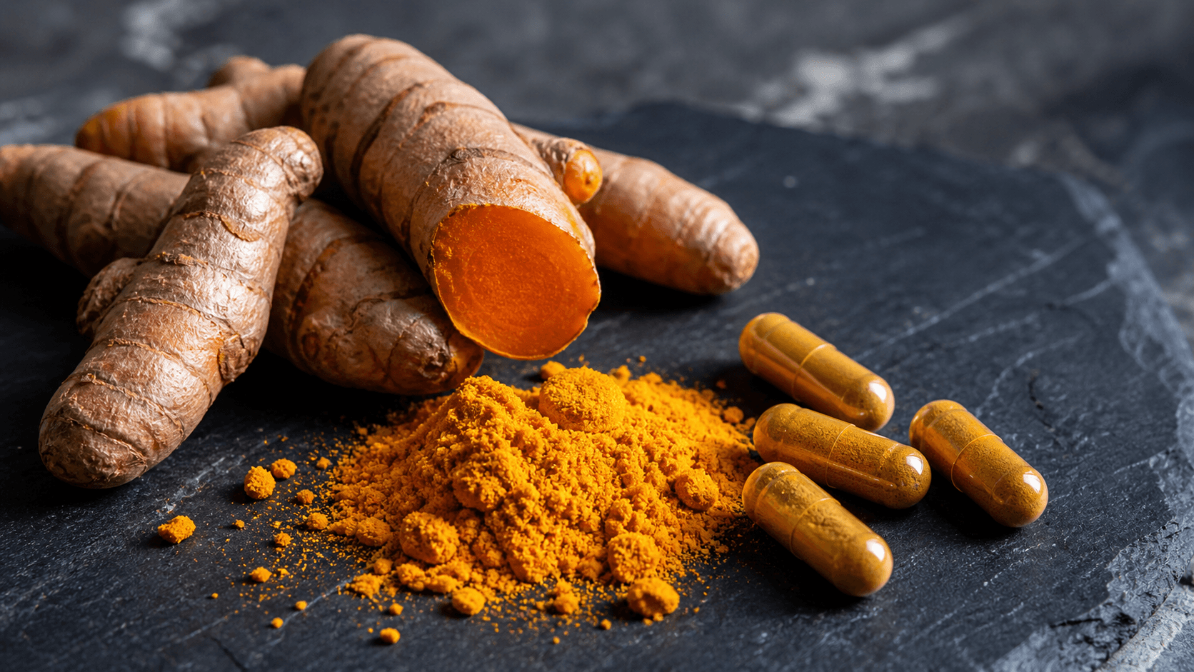 Golden turmeric root and powder alongside curcumin supplement capsules on a clean surface