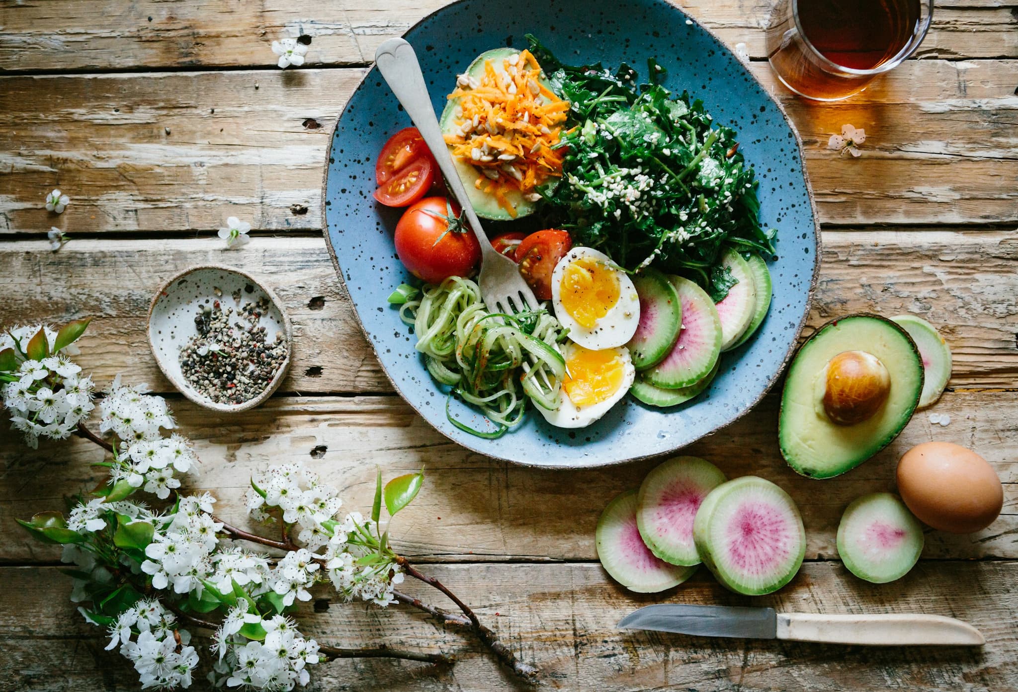 Overhead shot of a keto meal with eggs, bacon, avocado and fresh herbs in a dark stone bowl